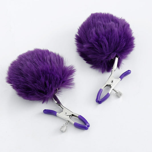 Pom-pom nipple clamps in purple with adjustable tension and rubber-tipped ends.