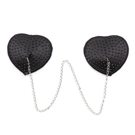 Black heart-shaped rhinestone nipple pasties with connecting chain on a white background.