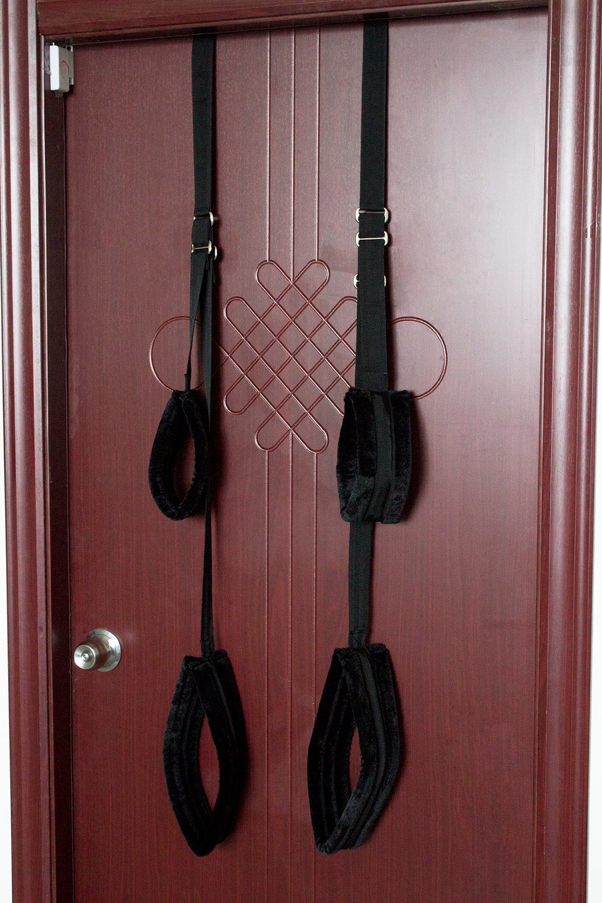 Black door sex swing with padded straps for bondage play, hanging on a red door. 
