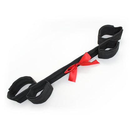 black bondage restraint strap with red satin bow and soft adjustable cuffs.