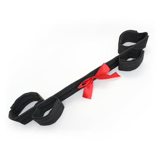 black bondage restraint strap with red satin bow and soft adjustable cuffs.
