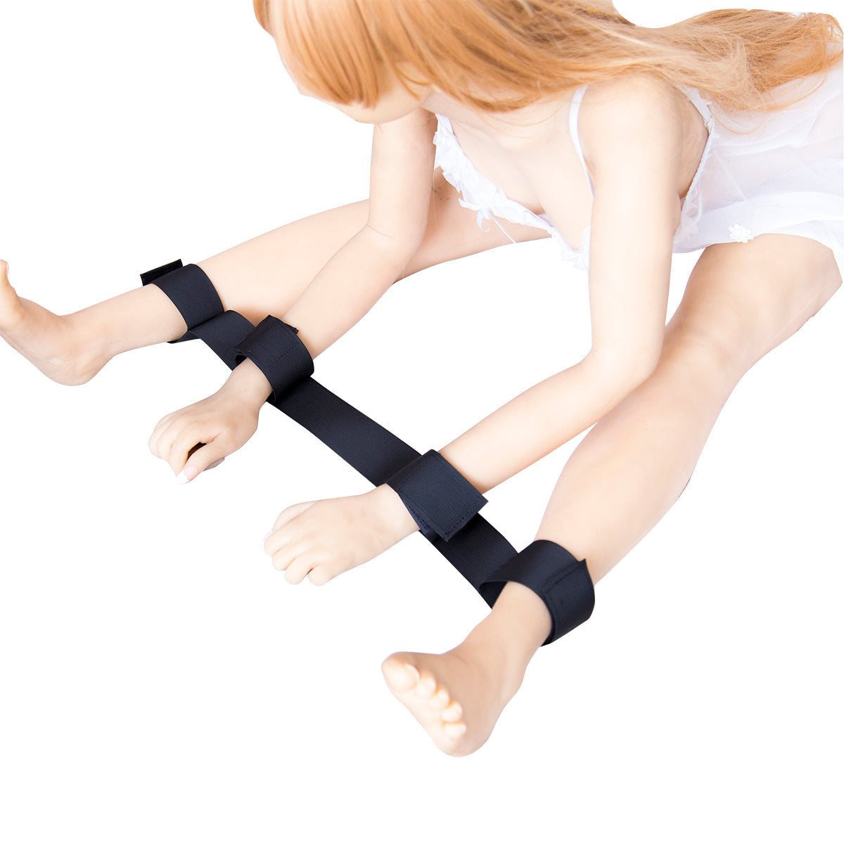 Woman wearing black spreader restraint strap with adjustable wrist and ankle cuffs.