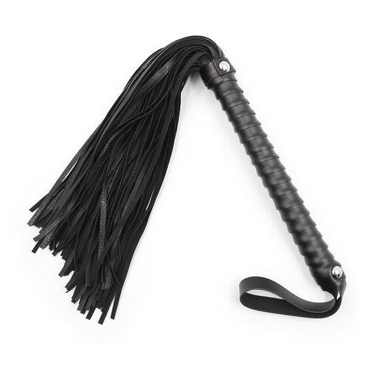 Black faux leather bondage whip with ribbed handle and wrist strap on a white background. 