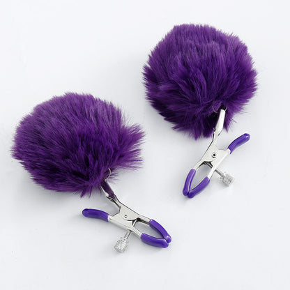 Pom-pom nipple clamps in purple with adjustable tension and rubber-tipped ends.