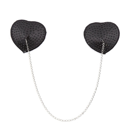 Black heart-shaped rhinestone nipple pasties with connecting chain on a white background. 