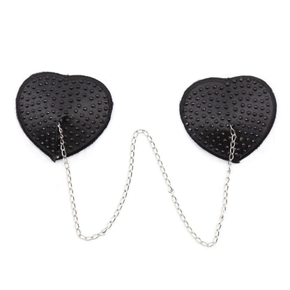 Black heart-shaped rhinestone nipple pasties with connecting chain on a white background. 
