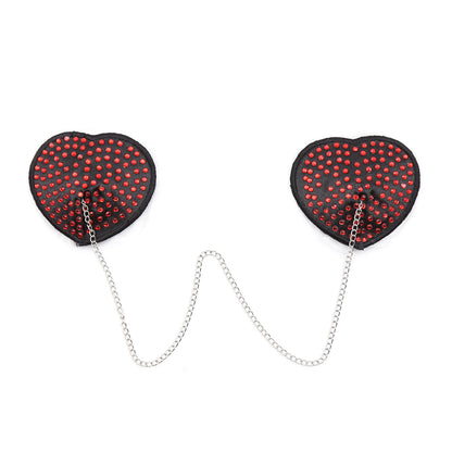 Red heart-shaped rhinestone nipple pasties with connecting chain on a white background. 