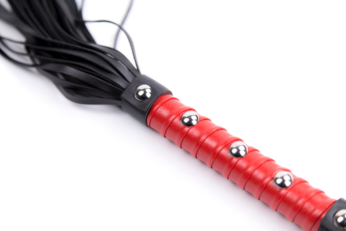 Red studded handle flogger with black faux leather tails.